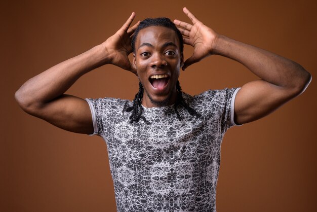 Young handsome African man against brown background