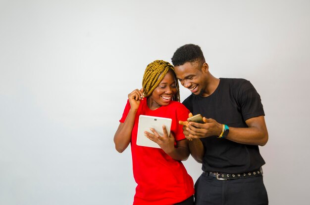 A young handsome african man and beautiful african lady isolated over white background both feeling highly excited about what they saw on their mobile phone