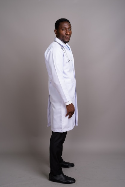 Young handsome African man doctor against gray background