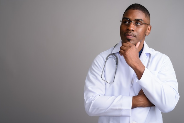 Young handsome African man doctor on gray