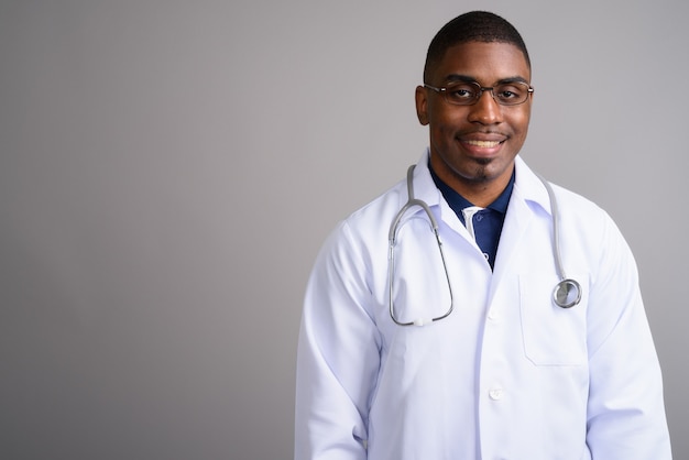 Young handsome African man doctor on gray