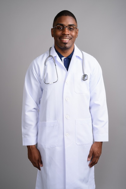 Young handsome African man doctor on gray