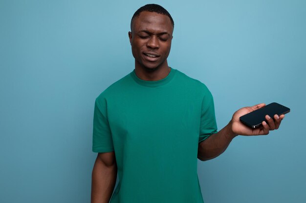 Young handsome african man dressed in tshirt uses smartphone for social media on isolated background