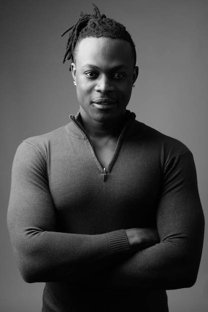  young handsome African man from Kenya against gray wall in black and white