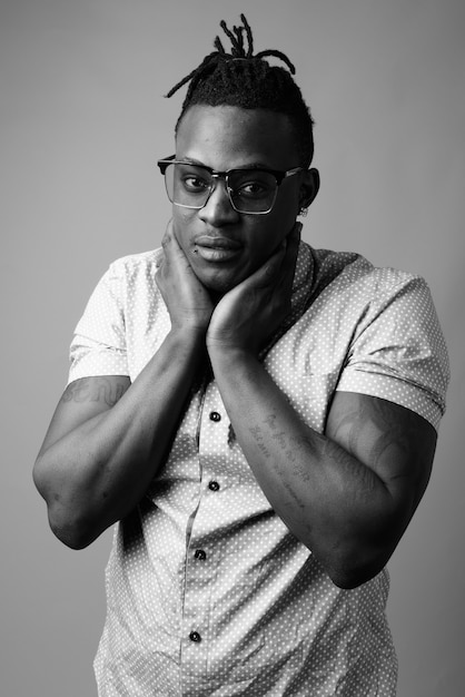  young handsome African man from Kenya against gray wall in black and white