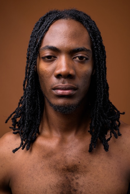 Photo young handsome african man shirtless against brown background