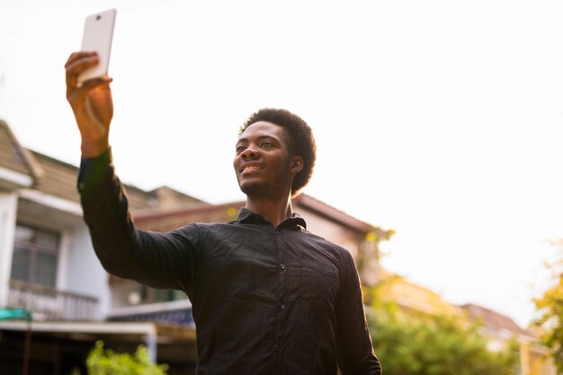 Bel giovane uomo africano utilizzando il telefono cellulare all'aperto