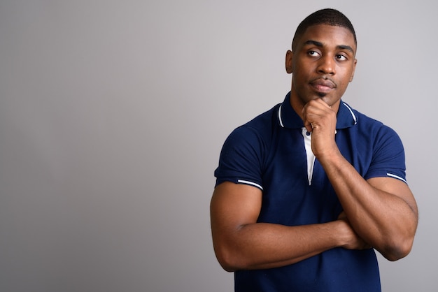 Young handsome African man wearing blue polo shirt on gray