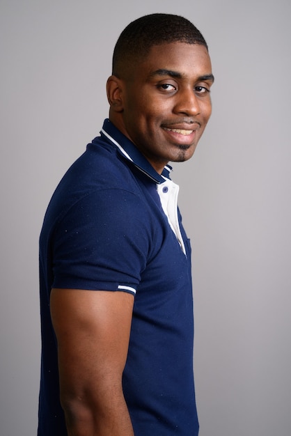 Photo young handsome african man wearing blue polo shirt on gray