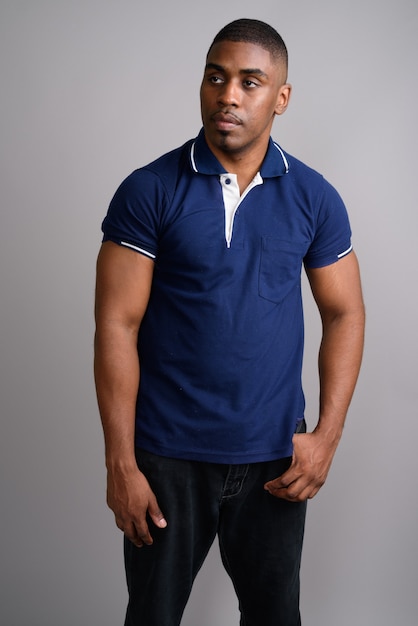 Young handsome African man wearing blue polo shirt on gray