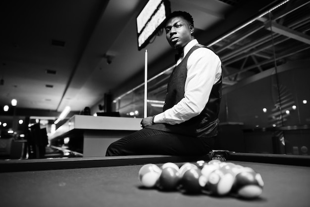 Photo young handsome african man wearing white shirt black vest and bow tie play pool billiard