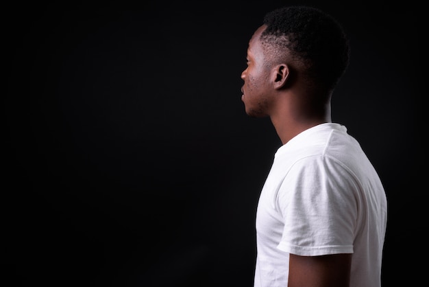 young handsome African man with Afro hair against black wall