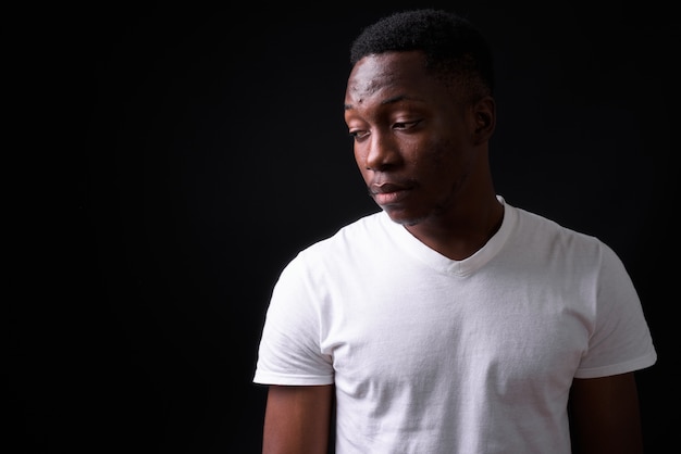 Photo young handsome african man with afro hair against black wall