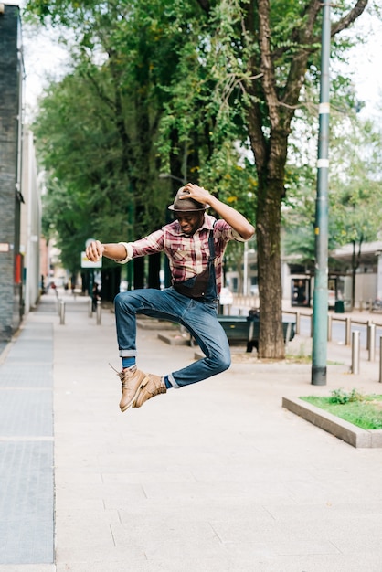 Young handsome afro back man jumping in the street of the city