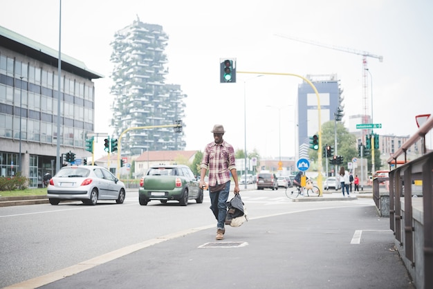 Giovane uomo di colore afro bello che cammina in strada della città