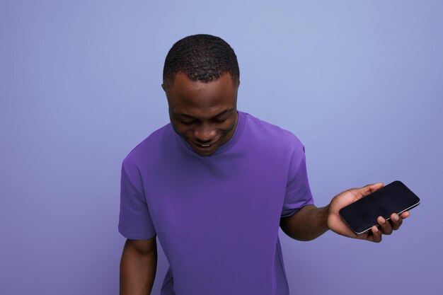 Young handsome american guy dressed in a basic tshirt holds a smartphone in his hand
