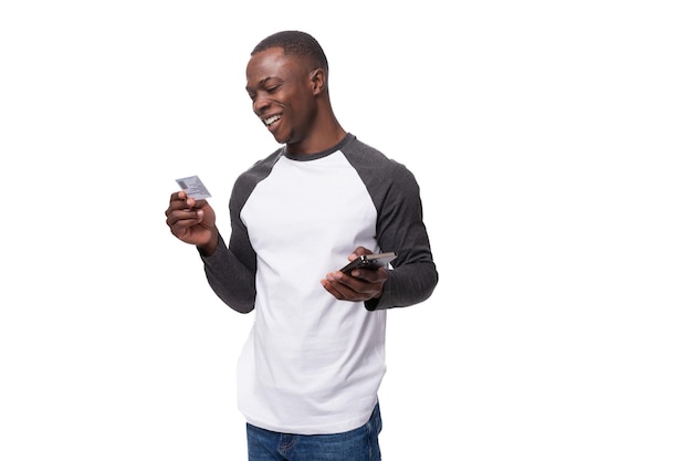 Photo young handsome american man dressed in a longsleeved sweater reads information on a bank card and