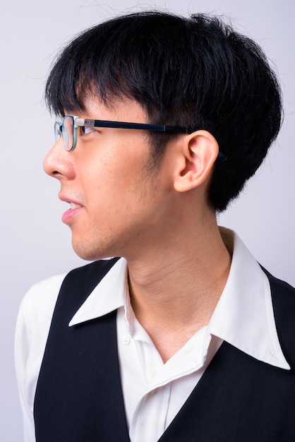 young handsome Asian businessman against white wall