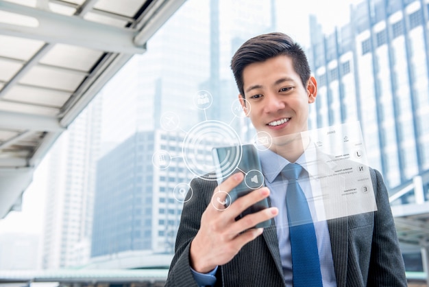 Photo young handsome asian businessman using mobile phone with virtual screen display