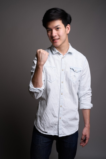 young handsome Asian businessman wearing white shirt on gray