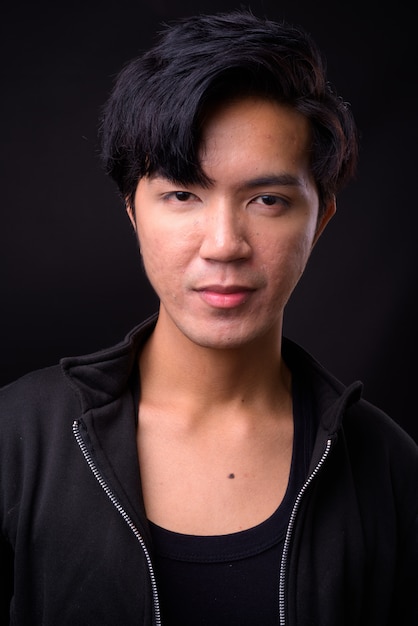 Young handsome Asian man on black