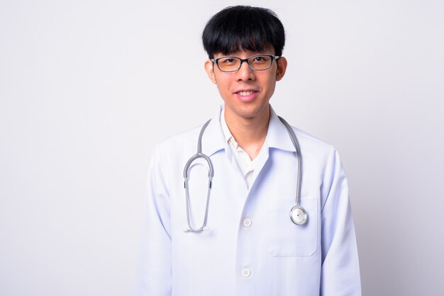  young handsome Asian man doctor against white wall