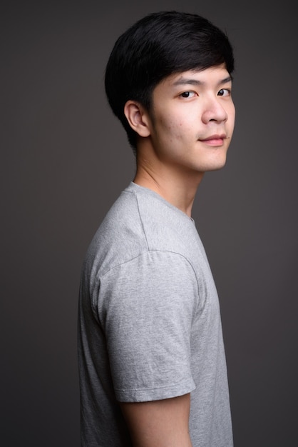 young handsome Asian man on gray