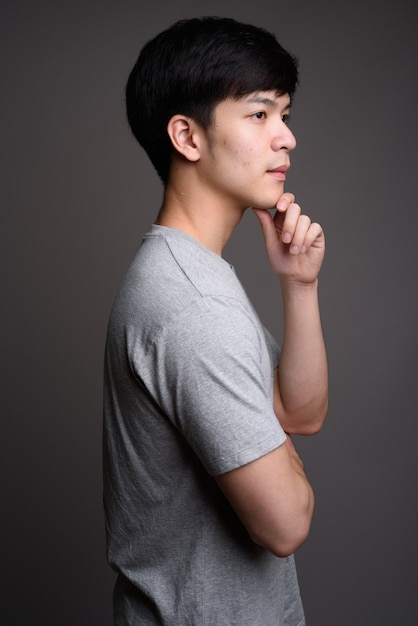 young handsome Asian man on gray