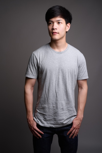 young handsome Asian man on gray