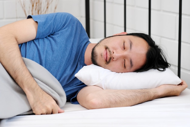 Young handsome asian man sleeping on white pill in bed, people lifestyle