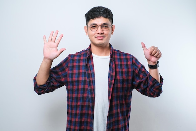 Young handsome Asian man wearing casual clothes showing and pointing up with fingers number six while smiling confident and happy