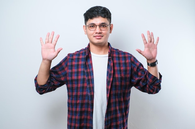 Young handsome Asian man wearing casual clothes showing and pointing up with fingers number ten while smiling confident and happy