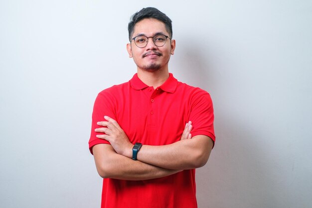 Young handsome Asian man wearing casual shirt keeping arms crossed and smiling while standing looking at camera