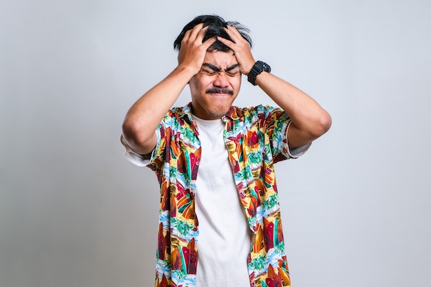 Young handsome asian man wearing casual shirt standing over isolated white background with hand on head for pain in head because stress. Suffering migraine.