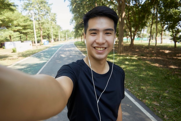 Photo young handsome asian men selfie looking at the camera and walking exercise in the park