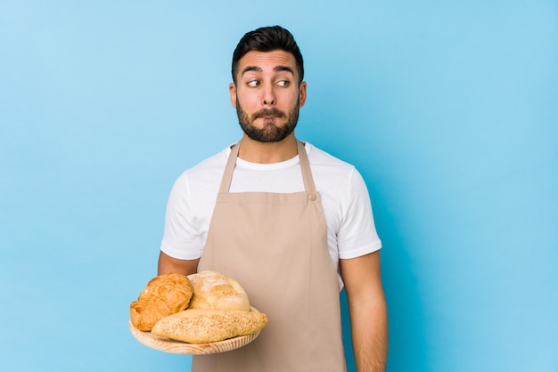 Young handsome baker confused, feels doubtful and unsure.