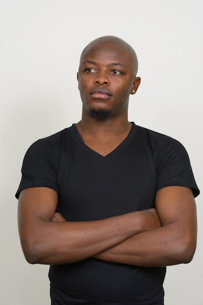 Young handsome bald African man thinking with arms crossed