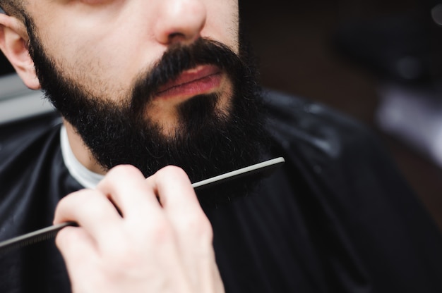 Giovane barbiere bello che fa taglio di capelli dell'uomo attraente