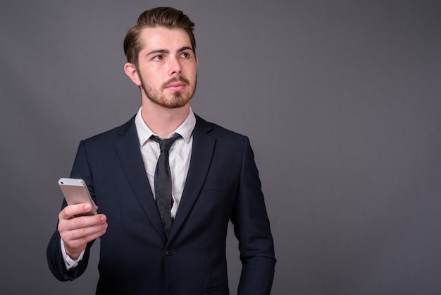 Young handsome bearded businessman against gray wall