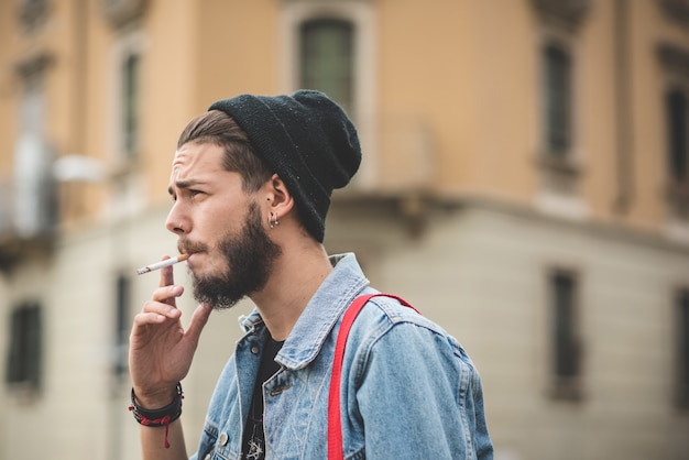 young handsome bearded hipster man smoking cigarette