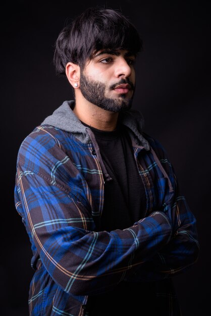 young handsome bearded Indian man against black