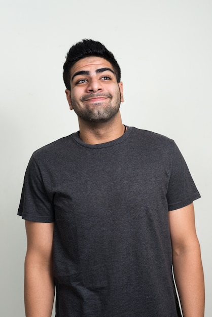 young handsome bearded Indian man against white wall