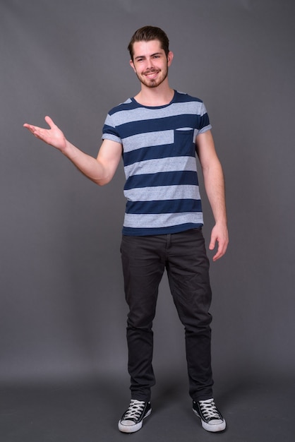 Young handsome bearded man against gray wall