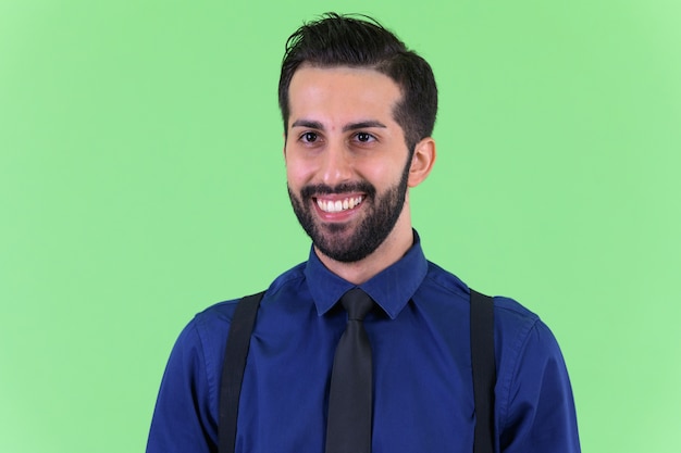  young handsome bearded Persian businessman against green wall