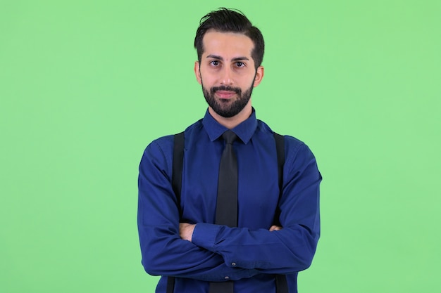  young handsome bearded Persian businessman against green wall