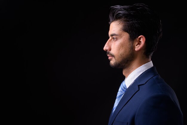 Foto giovane uomo d'affari persiano barbuto bello sul nero