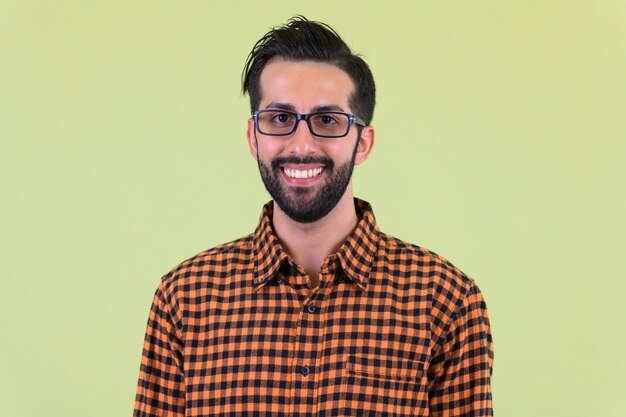 young handsome bearded Persian hipster man against colored wall