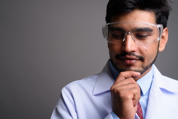 young handsome bearded Persian man doctor wearing protective glasses 