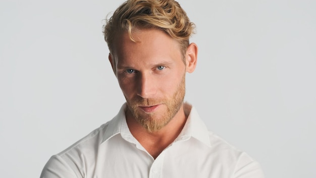 Young handsome blond bearded businessman in shirt looking serious on camera isolated on white background Confident man in shirt