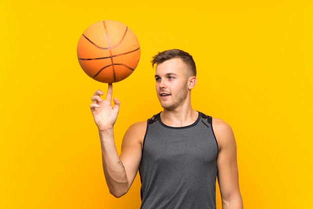 Young handsome blonde man holding a basket ball